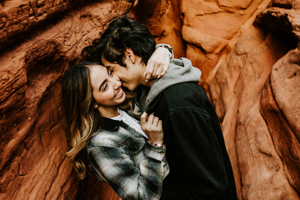 boy whispering in fiances ear in a red rock canyon