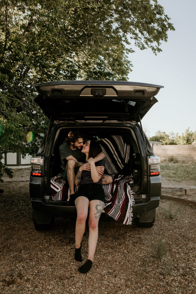 husband and wife holding each other against their suv