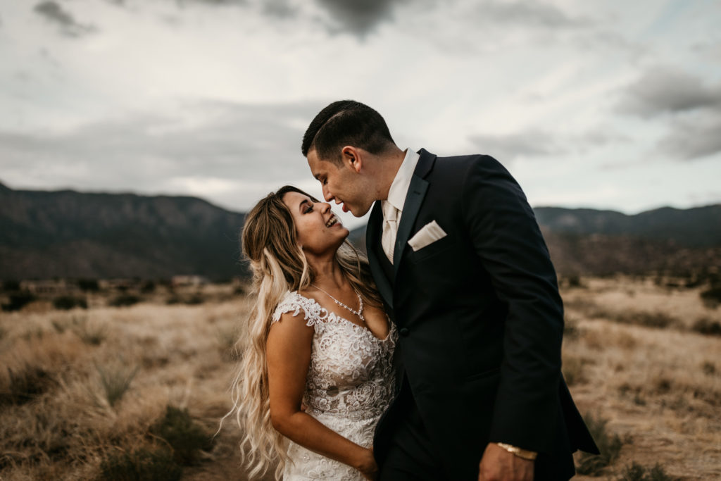 bride and groom about to kiss in front of a mountain