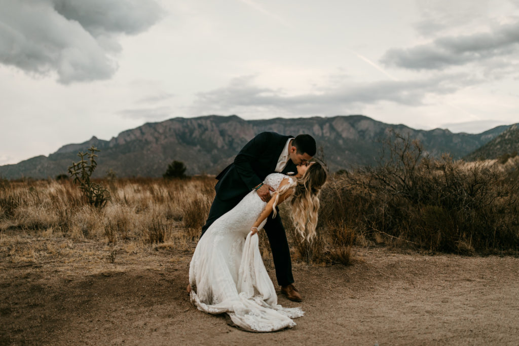 husband dipping and kissing wife in the desert