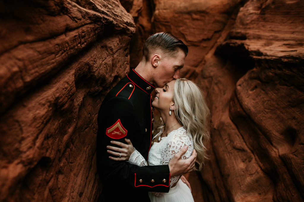 groom kissing brides forhead in a red rock canyon