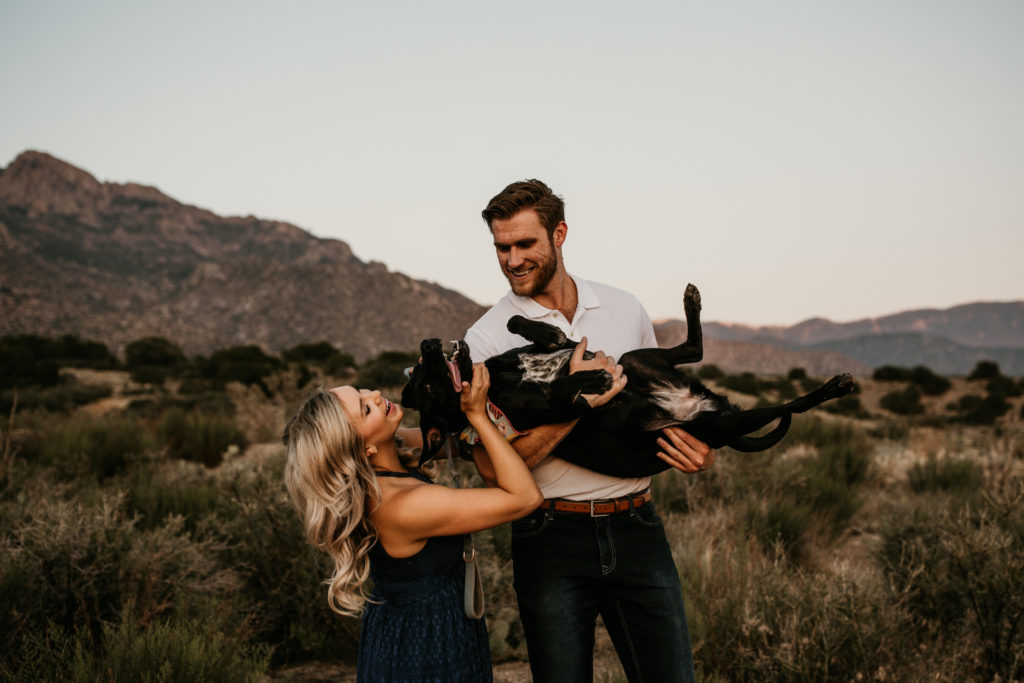 couple holding their dong on a mountain - tips for bringing your dog to your photo shoot 