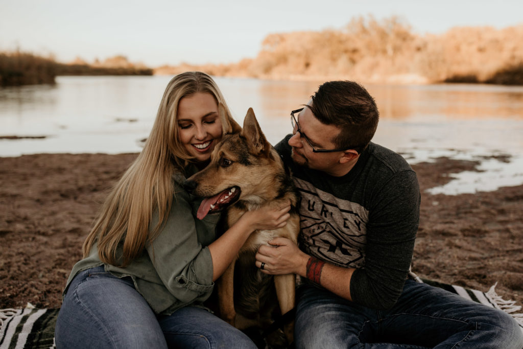 couple playing with dog by the river - tips for bringing your dog to your photo shoot 