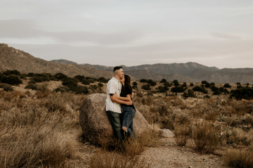 couple holding each other at the sandia mountain foothills in Albuquerque