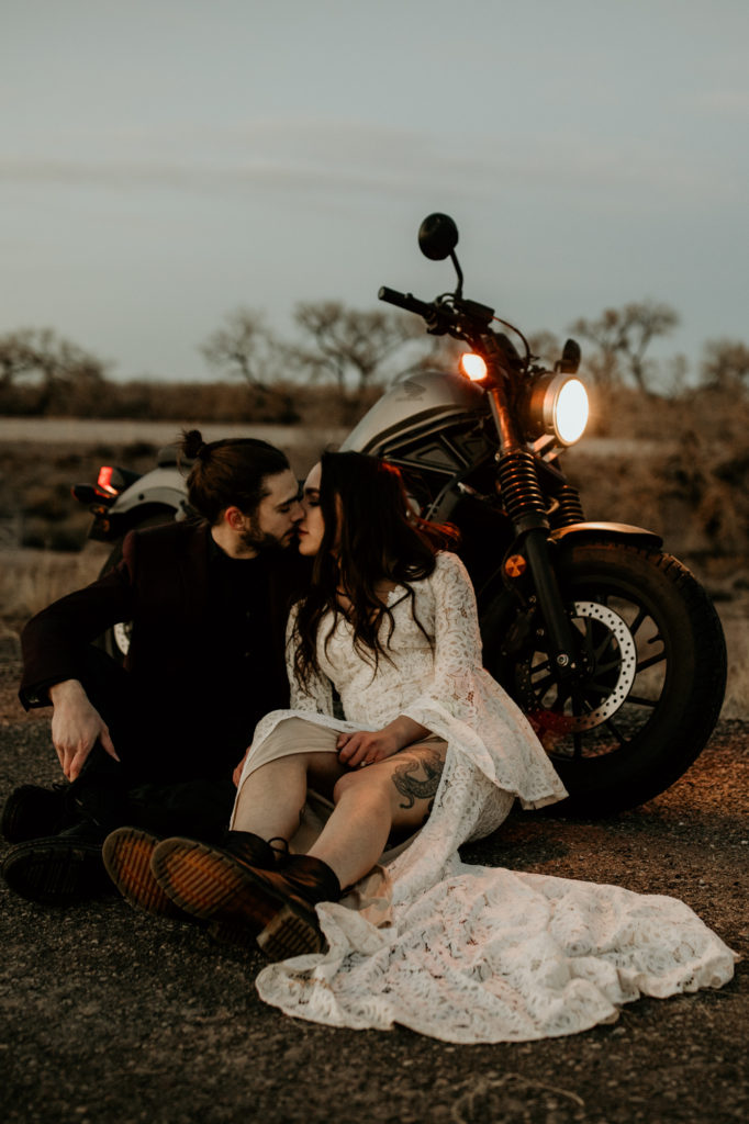 bride and groom sitting next to a motorcycle