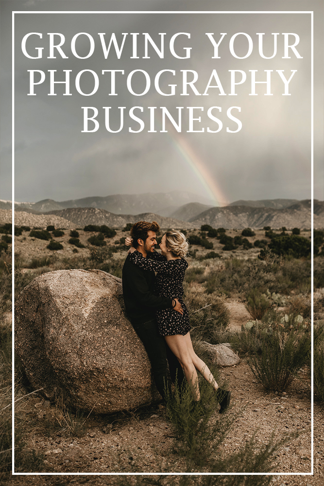 couple leaning on a rock in the desert with a rainbow behind them