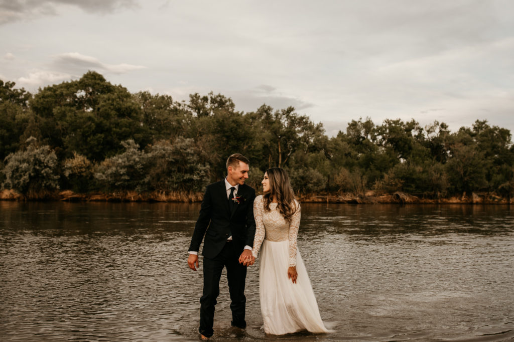 reason why couples elope - husband and wife walking through the rio grande river in their wedding attire