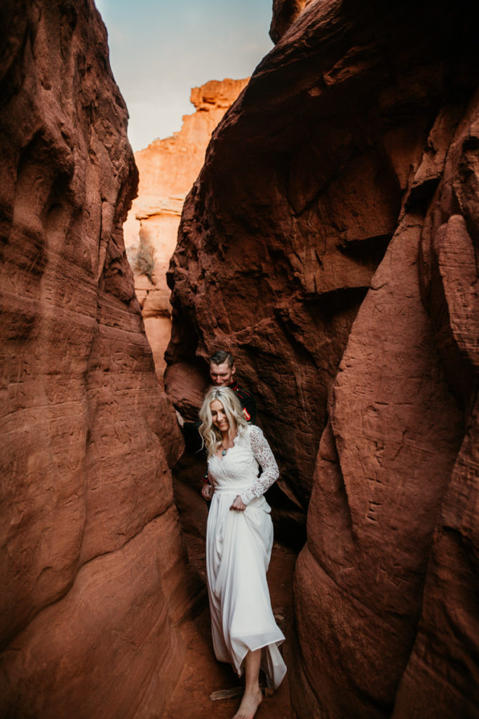 bride anf groom walking through a red rock canyon