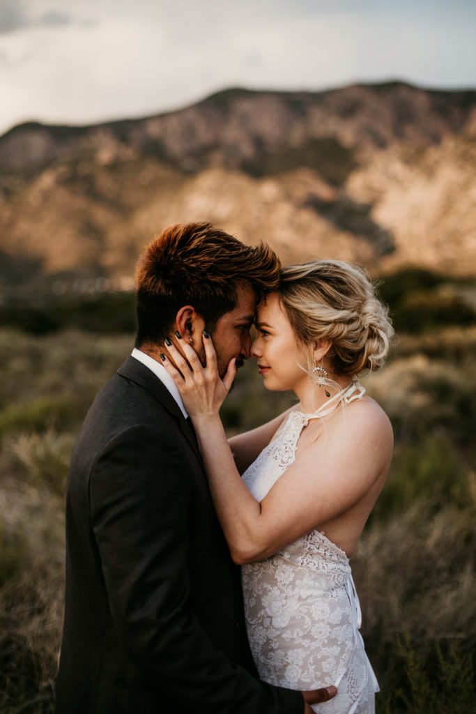 bride and groom holding each other in front of the sandia mountains in Albuquerque