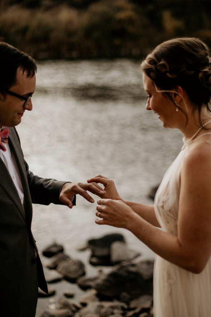 Bride and groom exchanging rings next to the rio grande river