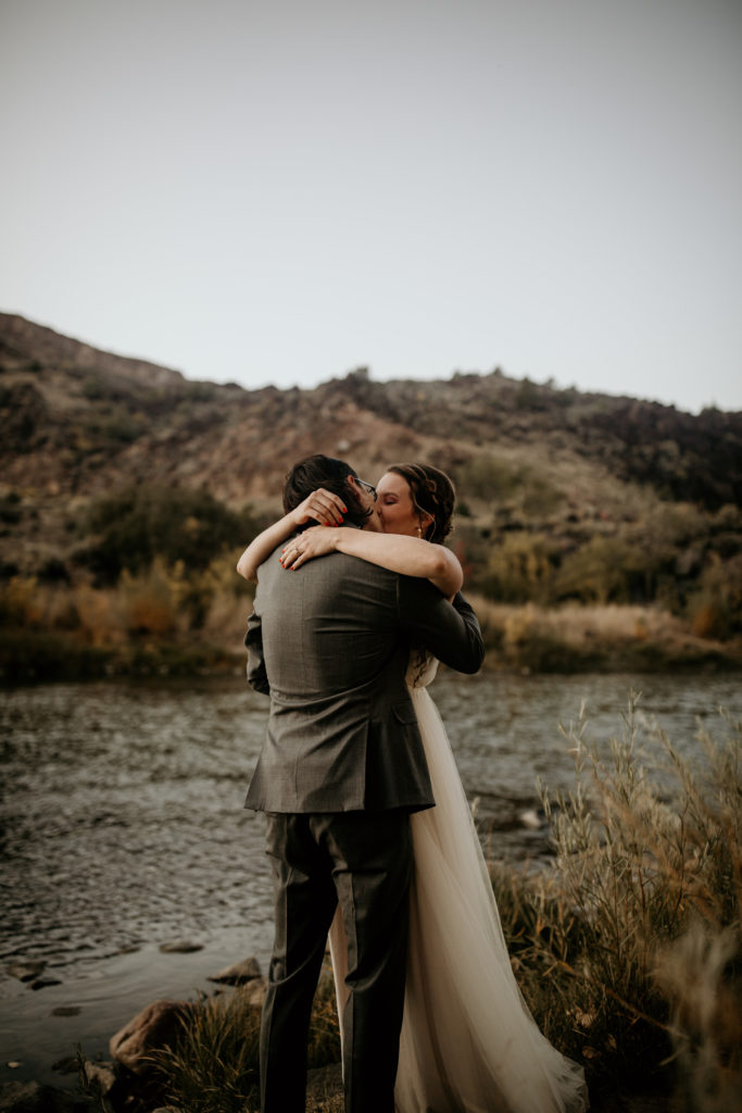 bride and groom having their first kiss in front of the Rio Grande river