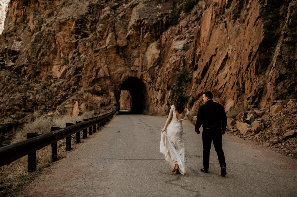 bride and groom walking towards a rock tunnel in new mexico