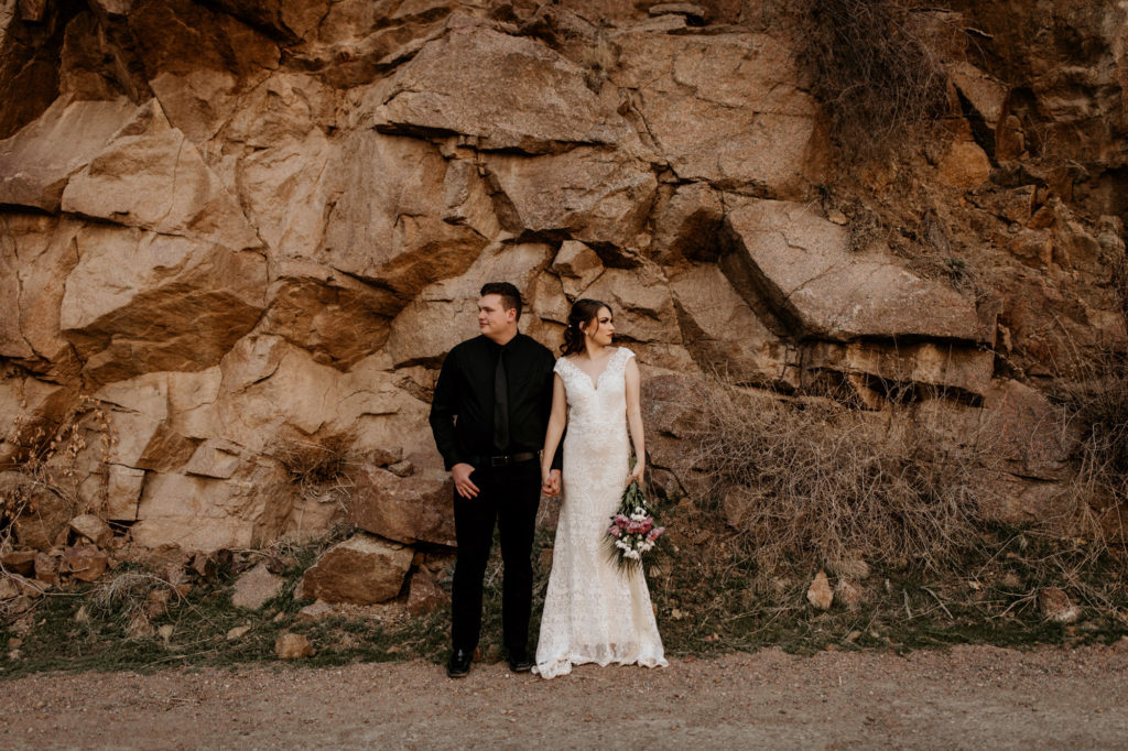 bride and grrom standing in front of rocks in New Mexico