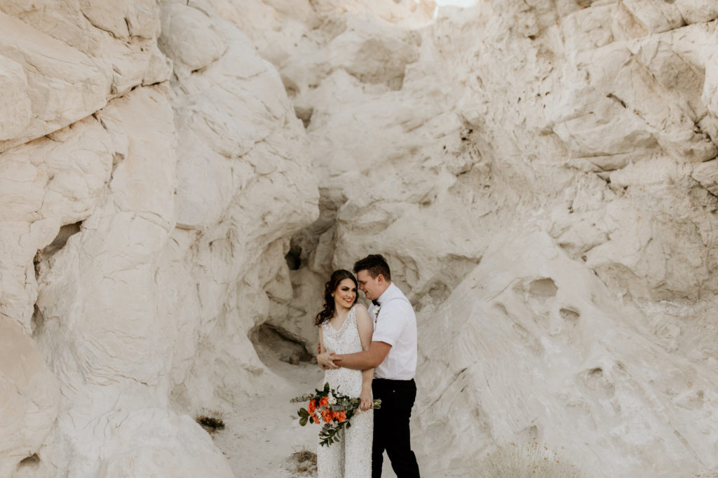 bride and groom standing in front of a white rock canyon