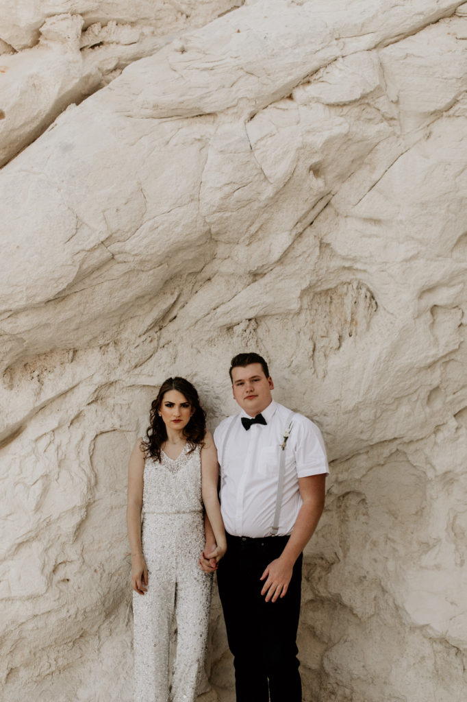 bride and groom standing in front of a white rock canyon