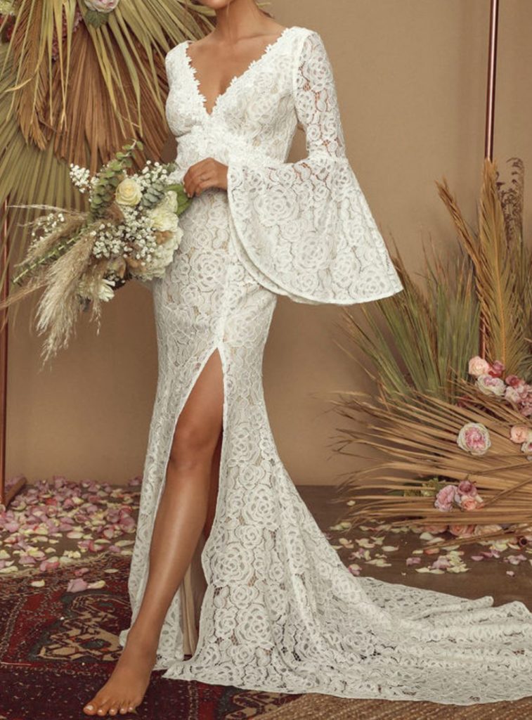 woman wearing a lace bell sleeve wedding dress holding a bouquet