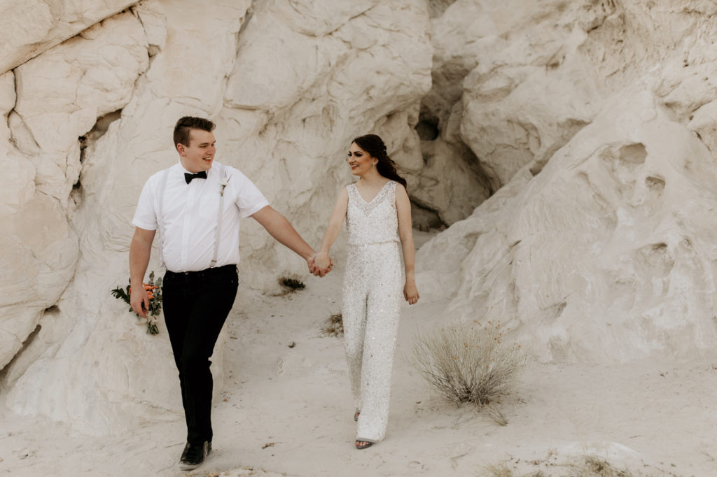 bride and groom walkign through a white rock canyon