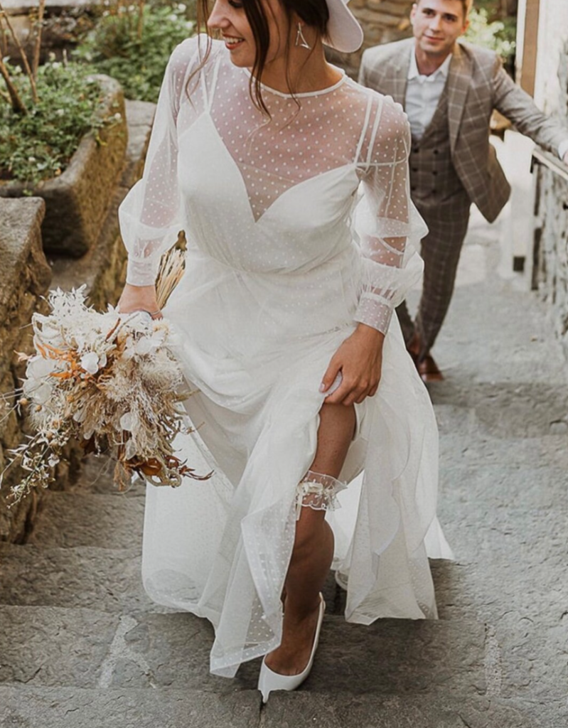 bride walking up stairs in a polka dot long sleeve wedding dress