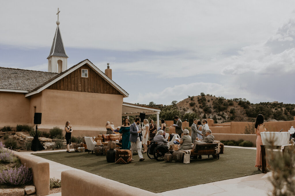 Intimate wedding party mingling outside of a chapel for cocktail hour in Santa Fe