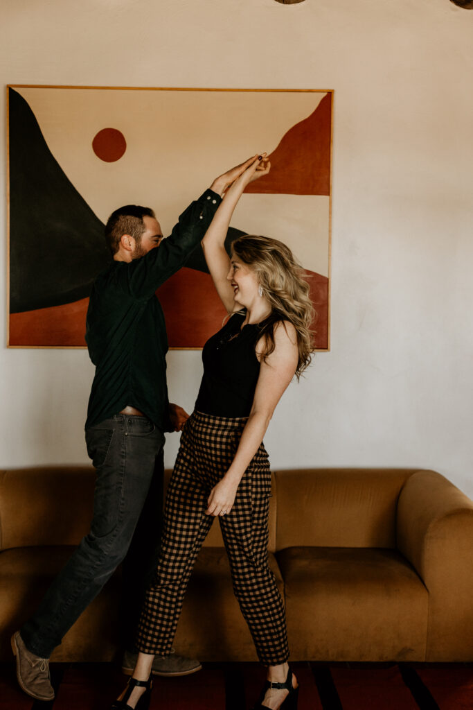 Engaged couple dancing together in a 70s styled room. 
