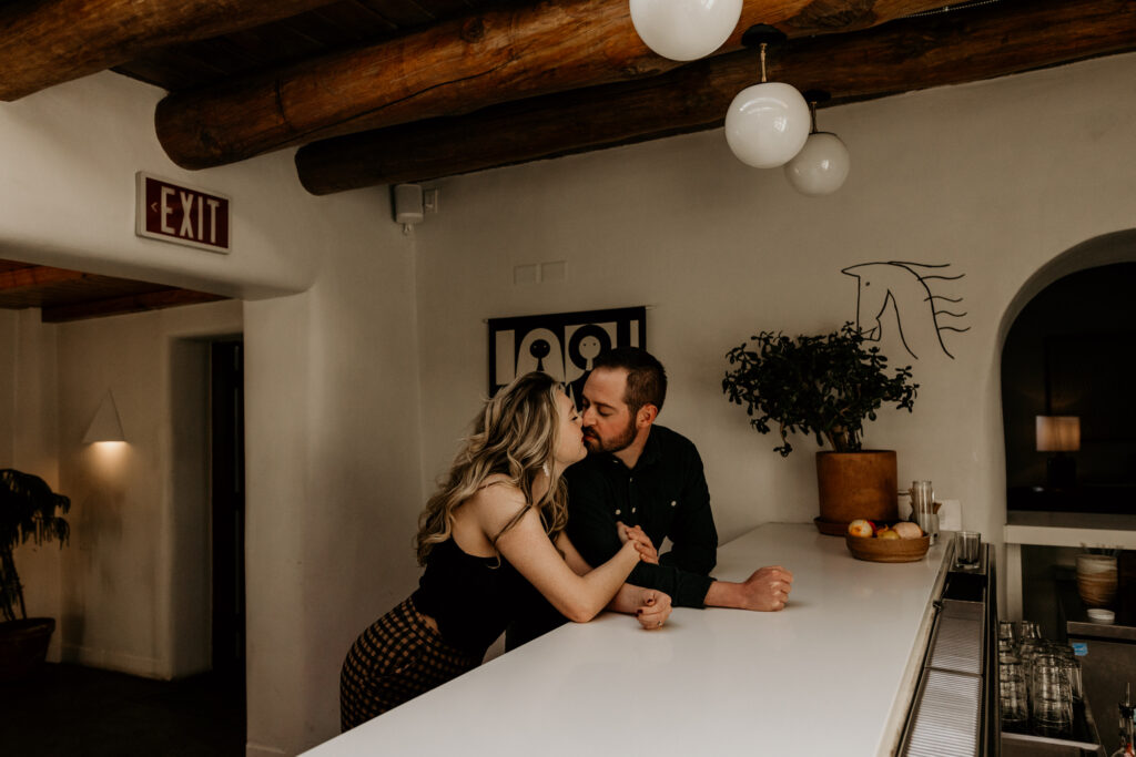 Engaged couple kissing each other at a southwest styled bar at a Intimate Wedding Venue in Santa Fe. 